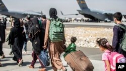 FILE - Families walk towards their flight during ongoing evacuations at Hamid Karzai International Airport, in Kabul, Afghanistan, Aug. 24, 2021, in this photo provided by the US Marine Corps.