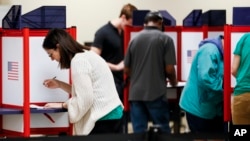 Voters fill out their ballots on the first day of early voting at the Hamilton County Board of Elections, Wednesday, Oct. 10, 2018, in Cincinnati. In-person voting has begun in swing-state Ohio for the Nov. 6 elections for governor, U.S. Senate, House seats and a host of other state and local offices and issues. Registration closed Tuesday, and county voting centers opened Wednesday morning. (AP Photo/John Minchillo)