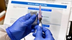 FILE - Nurse Kathe Olmstead prepares a shot that is part of a possible COVID-19 vaccine, developed by the National Institutes of Health and Moderna Inc., in Binghamton, New York, July 27, 2020.