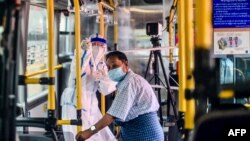 A health worker gestures to a man (R) receiving a checkup on a mobile health clinic on a bus during a medical checkup and contact tracing campaign in Yangon on September 9, 2020, as authorities work to halt the spread of the Covid-19 coronavirus. - Myanma