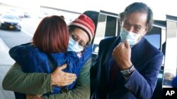 Danny Fenster, center, hugs his mother Rose Fenster as former U.S. diplomat Bill Richardson, right, looks on at John F. Kennedy Airport in New York, Nov. 16, 2021. 