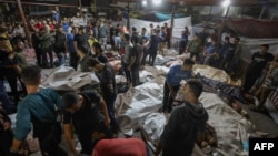 EDITORS NOTE: Graphic content / People gather around bodies of Palestinians killed in a strike on the Ahli Arab hospital in central Gaza after they were transported to Al-Shifa hospital, on October 17, 2023.