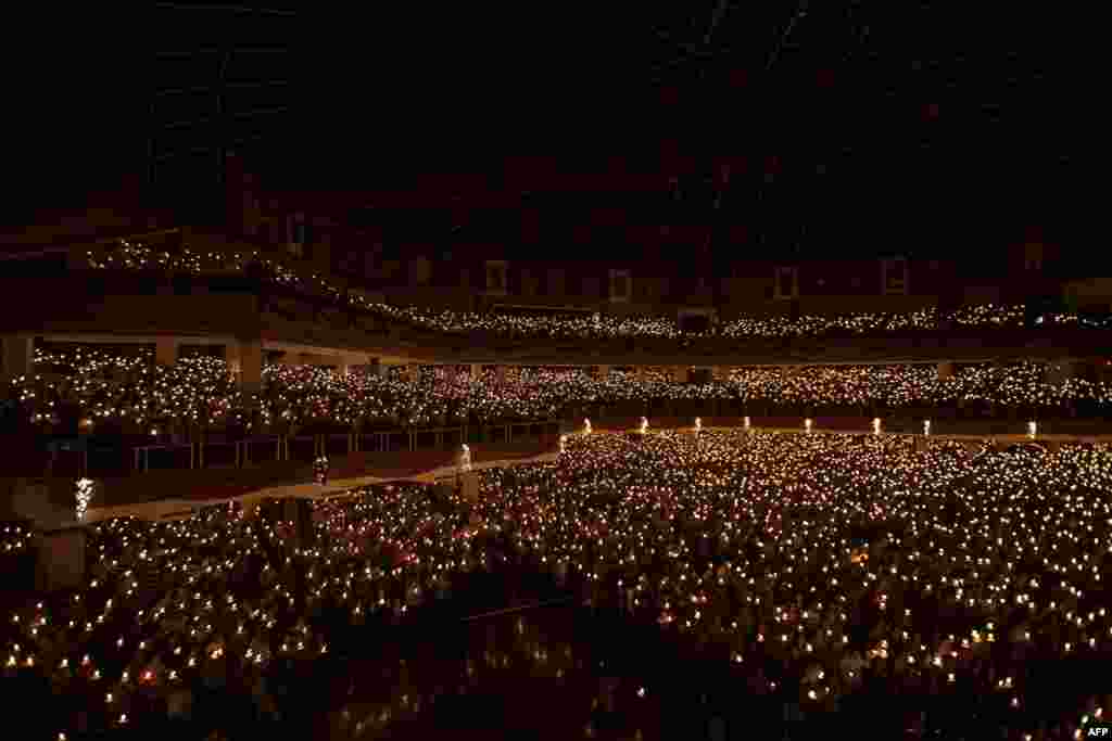 In this picture taken on December 24, 2014 Christians hold candles during the mass service in Surabaya, in the eastern Java island. Millions of Christians in Indonesia celebrated Christmas eve in the most populous Muslim country. AFP PHOTO / Juni KRISWANT