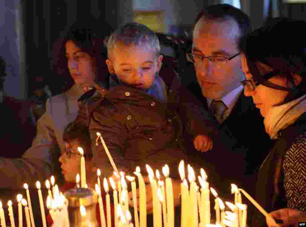 An Albanian boy lights a candle inside of the Resurrection of Christ Orthodox Cathedral, on Christmas day in Tirana, Dec. 25, 2015.